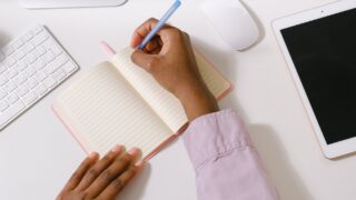 black woman with pen taking notes in planner